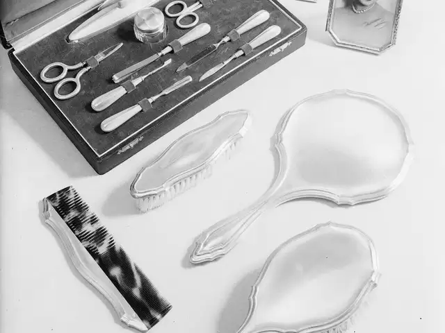 Une trousse de manucure en argent ouverte, ciseaux, limes et repoussoirs, avec brosses et miroir.